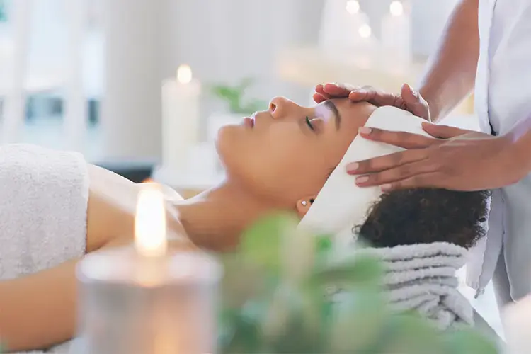 A woman lies relaxed on the treatment table. Candles burn around you.
